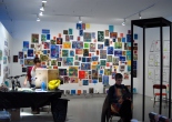 two woman in front of a cluster of small paintings on a white wall